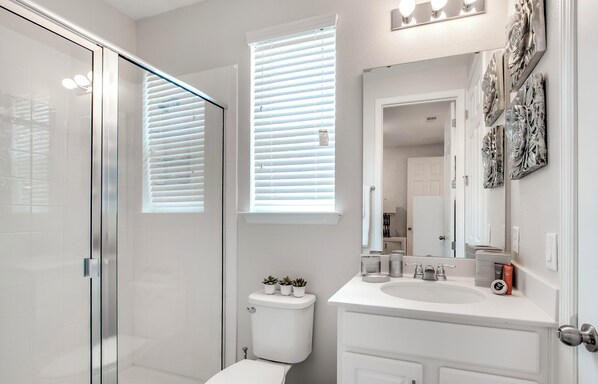 A modern bathroom with a glass shower enclosure, a toilet, and a vanity with a mirror.