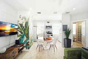 A modern kitchen with white cabinets, a microwave, and a dining area with a round table and chairs.