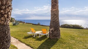 A grassy outdoor area with two lounge chairs and a view of the ocean. - The flair of Ibiza on the coast — Casa Morrás 41 (Felanitx)