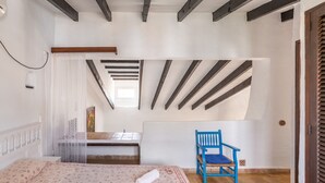 A bedroom with a bed, a chair, a desk, and a window. - The flair of Ibiza on the coast — Casa Morrás 41 (Felanitx)
