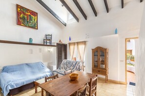 A room with a wooden table, a sofa, a cabinet, and a painting on the wall.
