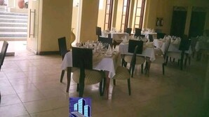 A dining area with multiple tables set for service, chairs, and a large window providing natural light. - Sun Paradise Nyali (Mombasa)