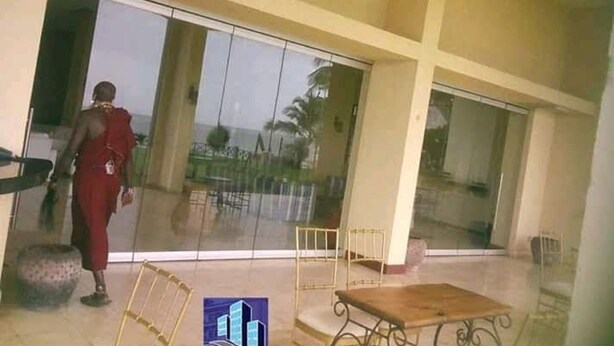 A spacious indoor area with a large sliding glass door, a small table, and a metal chair. - Sun Paradise Nyali (Mombasa)
