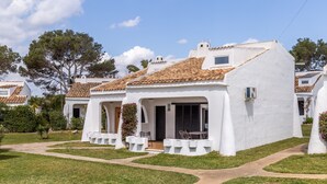 Une villa blanche avec un toit en tuiles, un jardin dallé et un ciel dégagé.