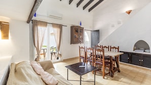 Un espace de vie chaleureux comprenant un canapé, une table à manger, des chaises et un coin cuisine avec un four encastré.