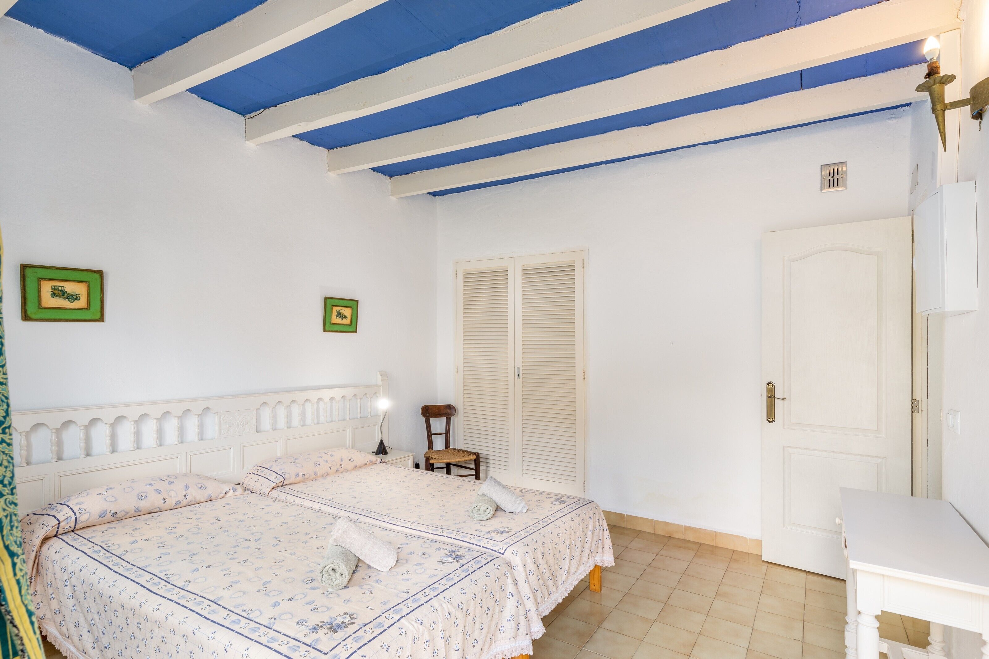 Une chambre à coucher avec un lit, une chaise, une table et une armoire.