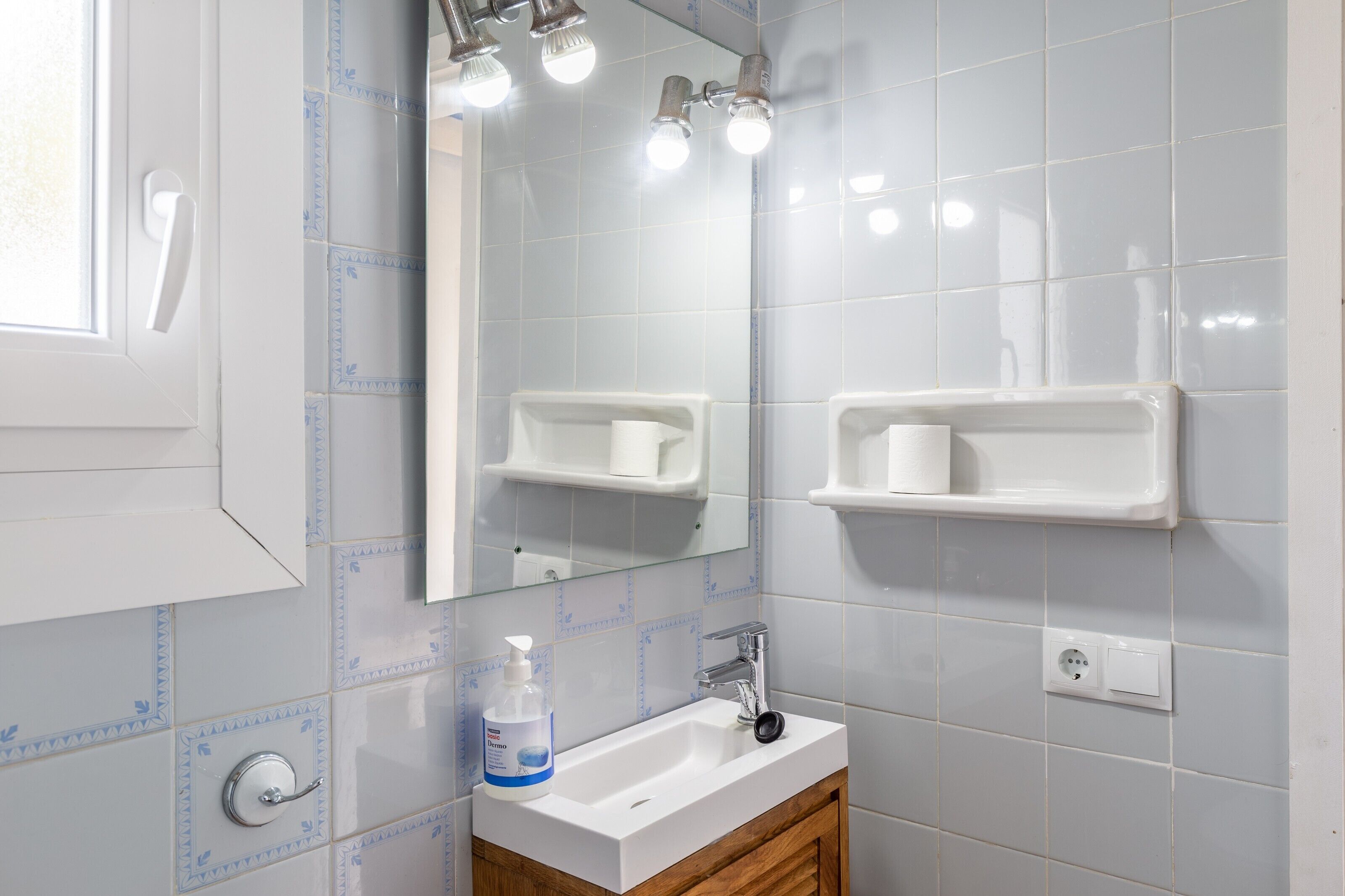A bathroom with a white sink, mirror, and two towel racks.