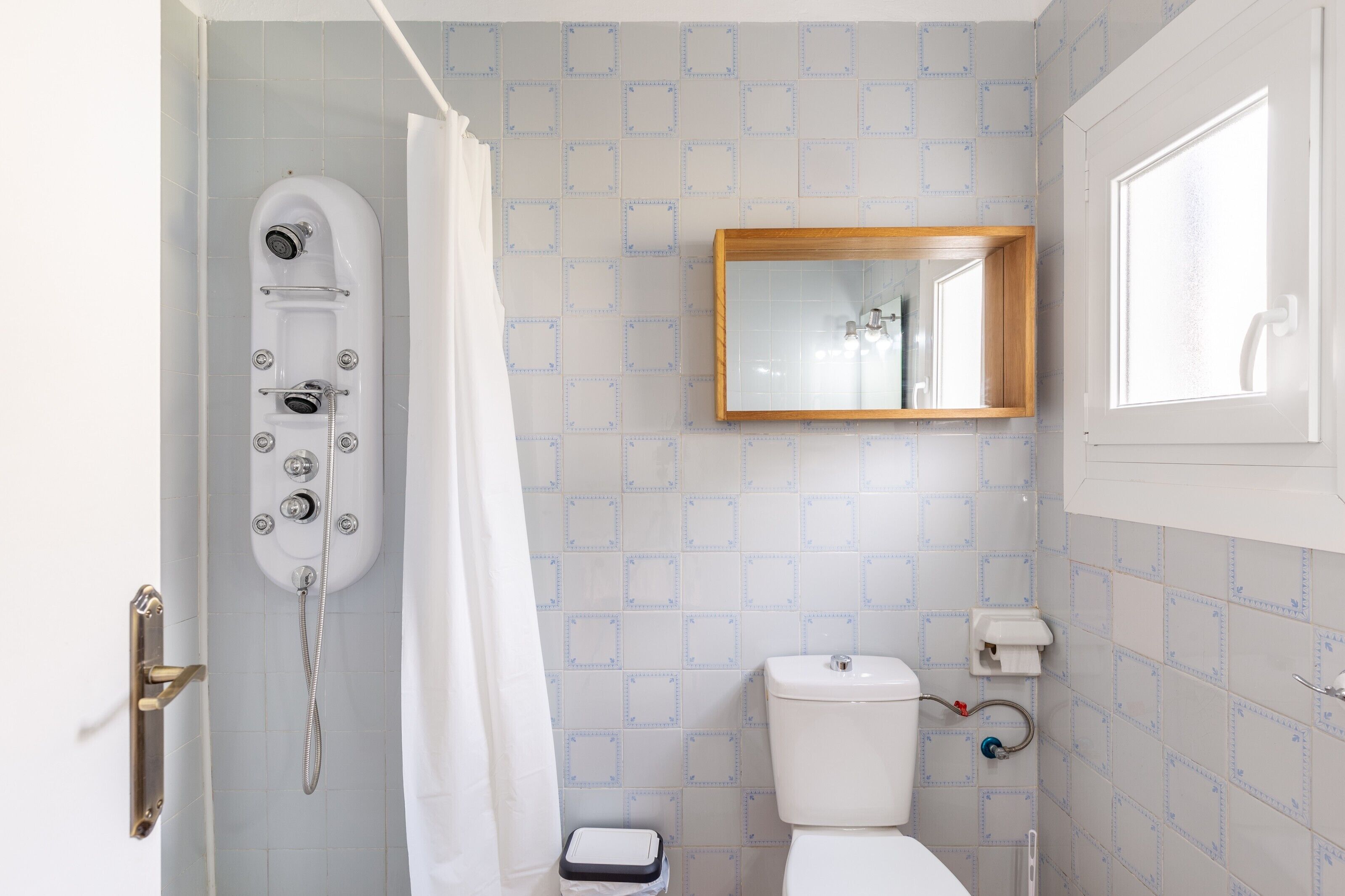 Een badkamer met douche, toilet en spiegel.