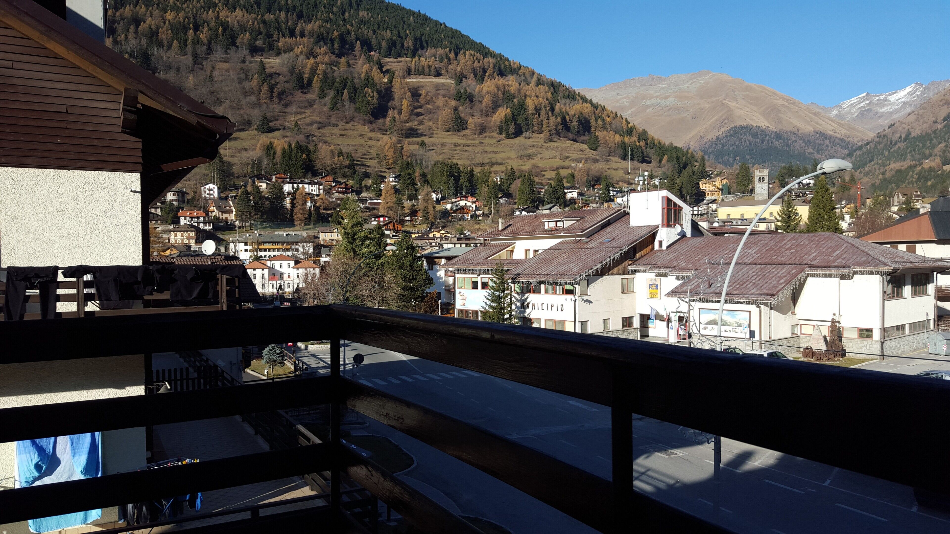 Un balcon donnant sur une ville avec des bâtiments, une route et des montagnes en arrière-plan.