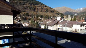 Un balcon donnant sur une ville avec des bâtiments, une route et des montagnes en arrière-plan.