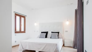 A bedroom with a bed, bedside lamps, a window, and a curtain.