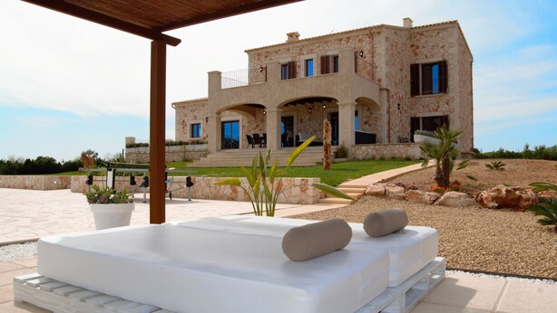 A modern house with a patio, outdoor seating, and a pool area.