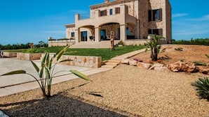 A two-story house with a stone facade, a front porch, and a landscaped garden.