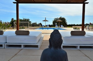 A pool area with lounge chairs, a statue, and a pergola.