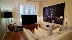 Relax in this stylish living room with a large flat-screen TV, comfortable sofa, and floor lamp.