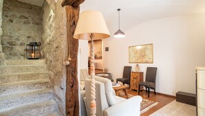 Una escalera de piedra que conduce a una sala de estar con una lámpara, sillas y un cuadro.