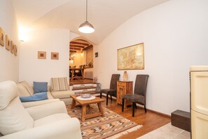 A living room with a sofa, chairs, a coffee table, a rug, and a painting on the wall.