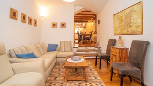 Una sala de estar con sofá, sillones, una mesa de centro y un comedor con mesa y sillas.