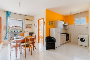 A modern kitchen with a dining area, a washing machine, and a view of the outside.