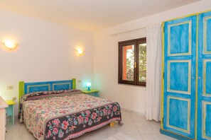 Ein Schlafzimmer mit Bett, Nachttischen, einem Fenster und einer blauen Tür.