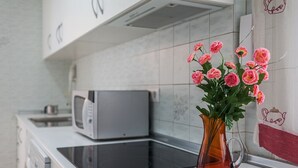 Eine Küche mit Mikrowelle, Induktionskochfeld und einer Vase mit Blumen auf der Arbeitsfläche.
