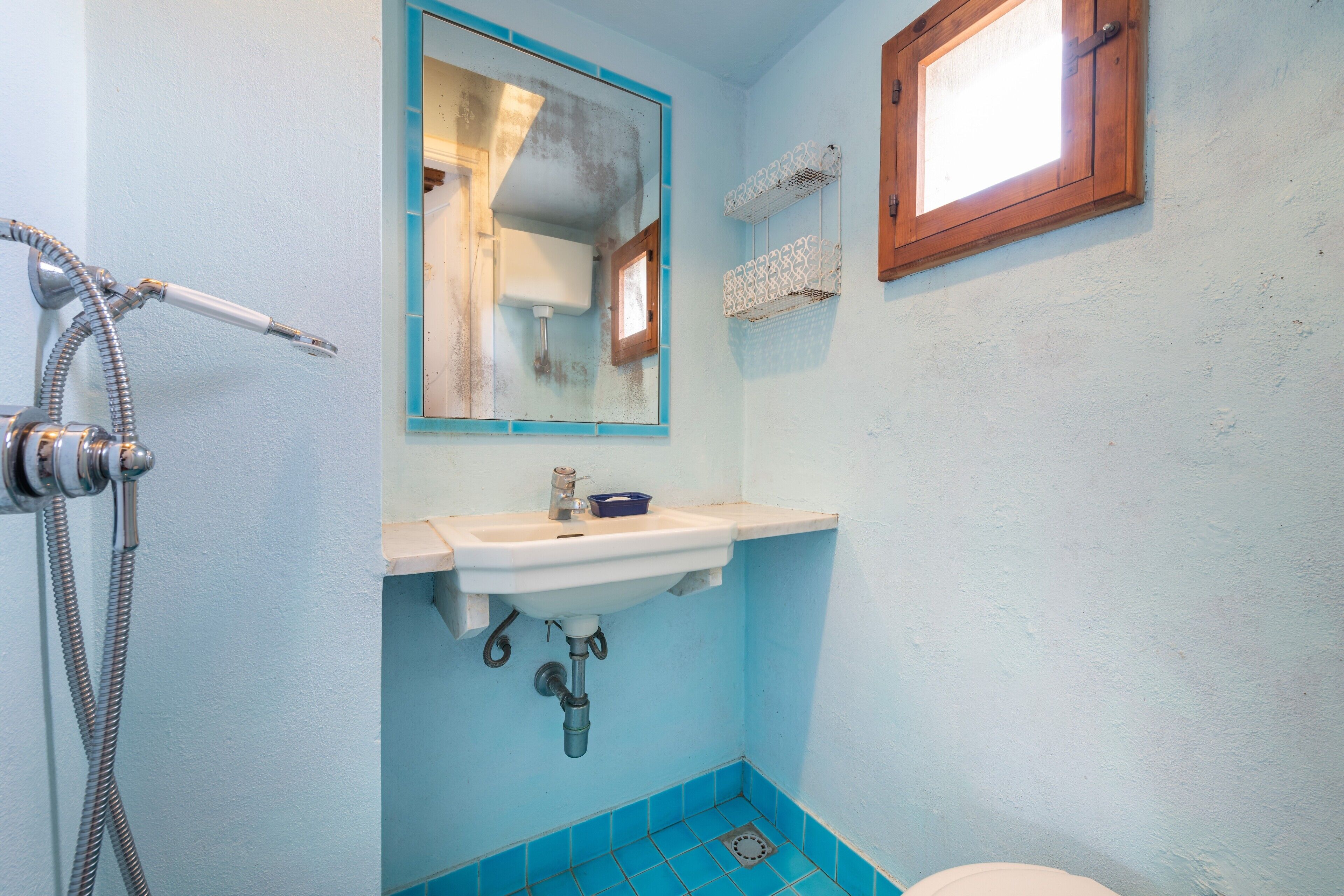 A bathroom with a sink, mirror, shower, and blue tiles.