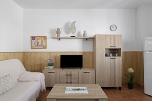 Uma sala de estar moderna com um sofá, uma TV, um armário e uma pequena mesa com um prato decorativo.