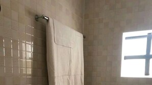 A bathroom with a toilet, a towel hanging on a rack, and a window. - The Loop Guest House and Restaurant (Eldoret)