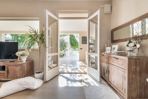 Ein Flur mit einem Holzschrank, einem Fernseher, einer Topfpflanze und einer Tür, die nach draußen führt.