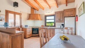 Una cocina con armarios de madera, una mesa de comedor con fruta y vistas al exterior.