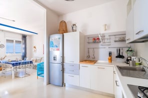 A modern kitchen with a refrigerator, sink, and dining area.