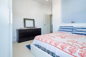 A bedroom with a bed, a dresser, a mirror, and a door.