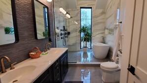 Ein modernes Badezimmer mit zwei Waschbecken, einem großen Spiegel, einer Dusche und einer Toilette.
