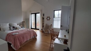 Ein Schlafzimmer mit Bett, Nachttisch, Stuhl und Schreibtisch mit Regalen.