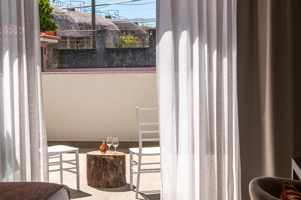 Une chambre à coucher avec un lit, une petite table ronde sur laquelle se trouvent une bouteille et un verre, et une chaise.