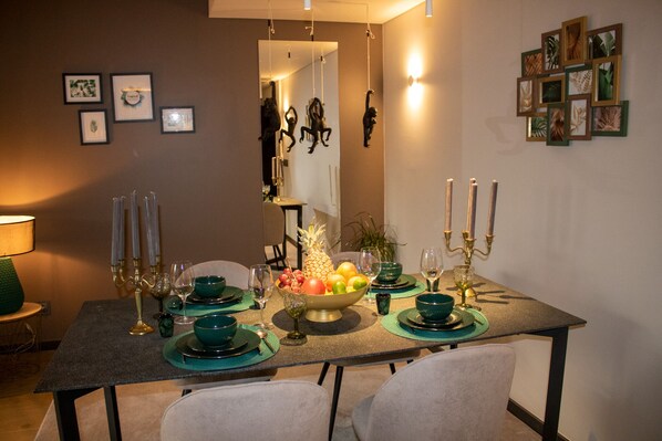 Comedor con una mesa dispuesta para cuatro personas, con platos, cuencos y candelabros verdes.