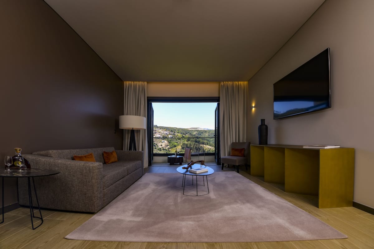Un salon moderne avec un canapé, une table basse, un téléviseur et une vue sur l’extérieur.