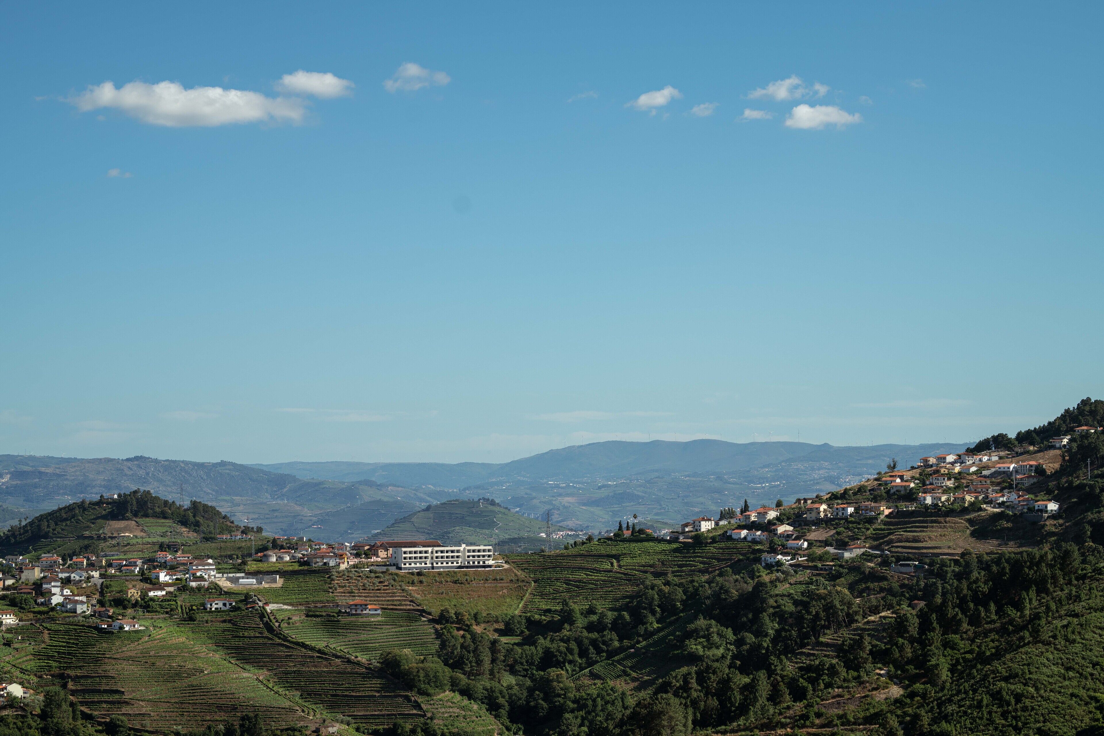 A rural landscape with terraced fields, a prominent white building, and scattered houses.