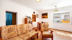 Un salon avec un canapé, des fauteuils, un meuble en bois et un tableau accroché au mur.