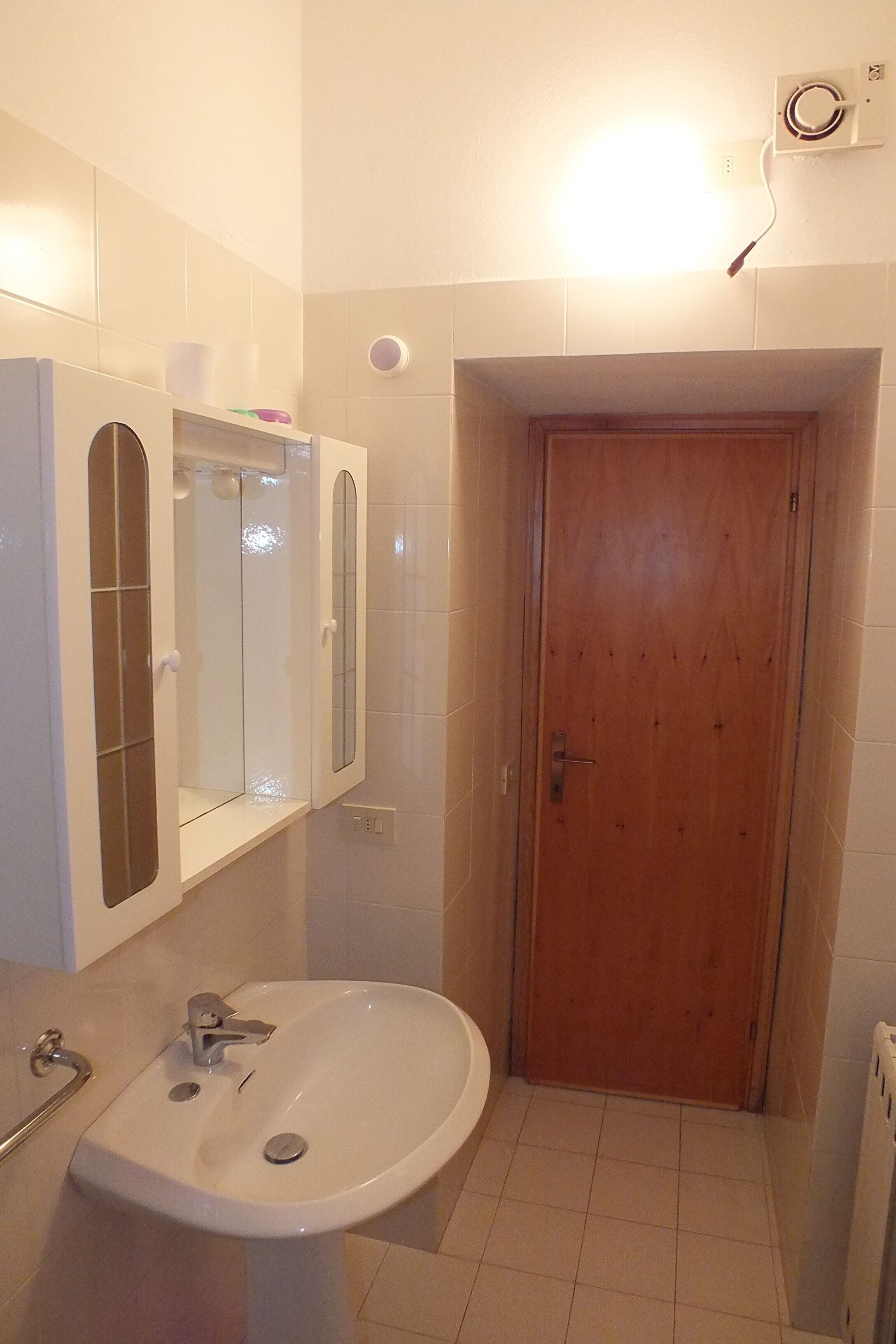 A bathroom with a sink, mirror, and wooden door.