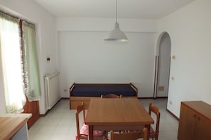 A dining area with a wooden table, chairs, a bench, and a hanging light fixture.
