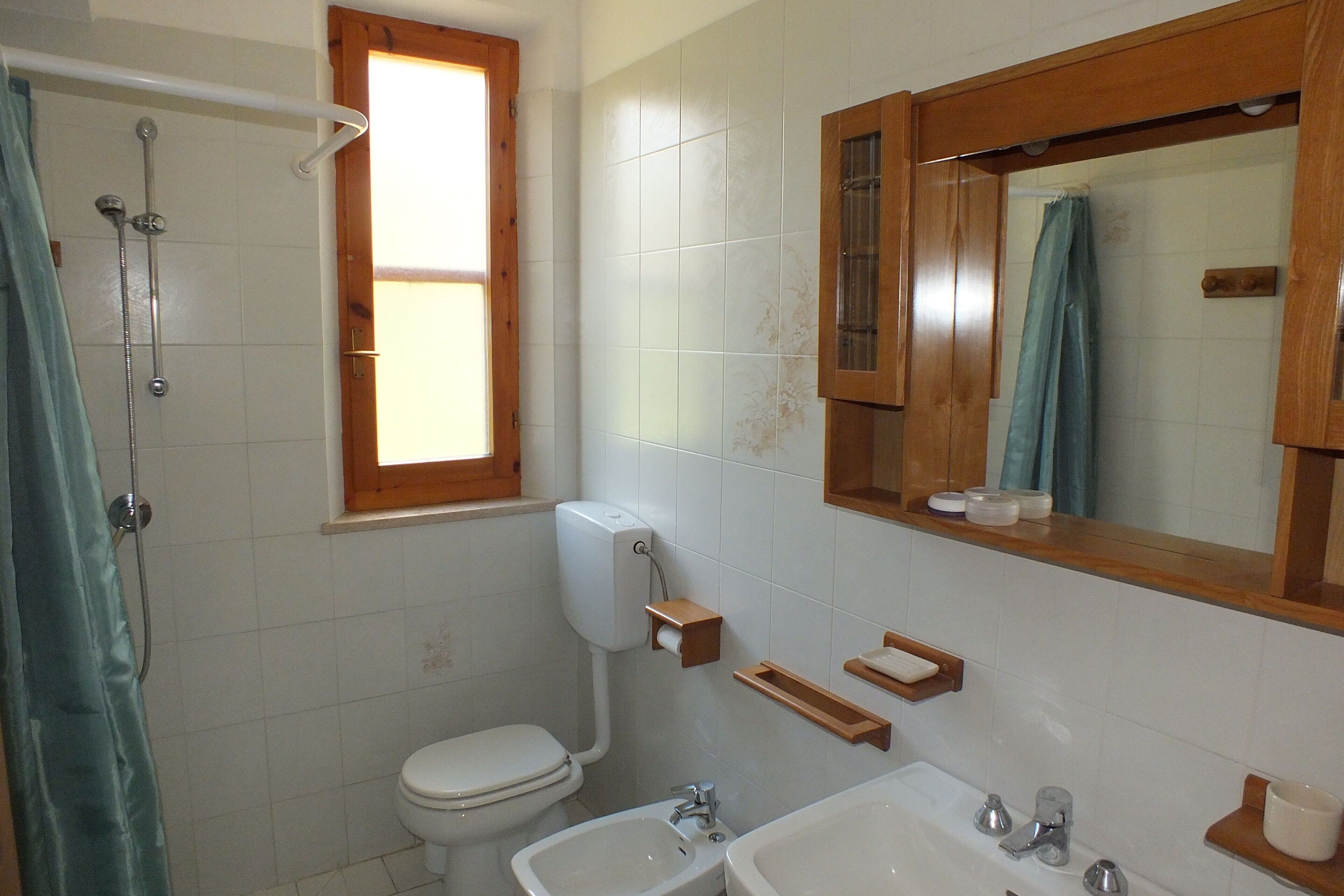 Een badkamer met toilet, bidet, wastafel en douche.