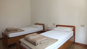 Two single beds with wooden frames, white linens, and folded towels.