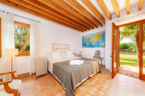 Une chambre à coucher avec un lit, un bureau, une chaise, une lampe, une carte accrochée au mur et une vue sur l’extérieur.