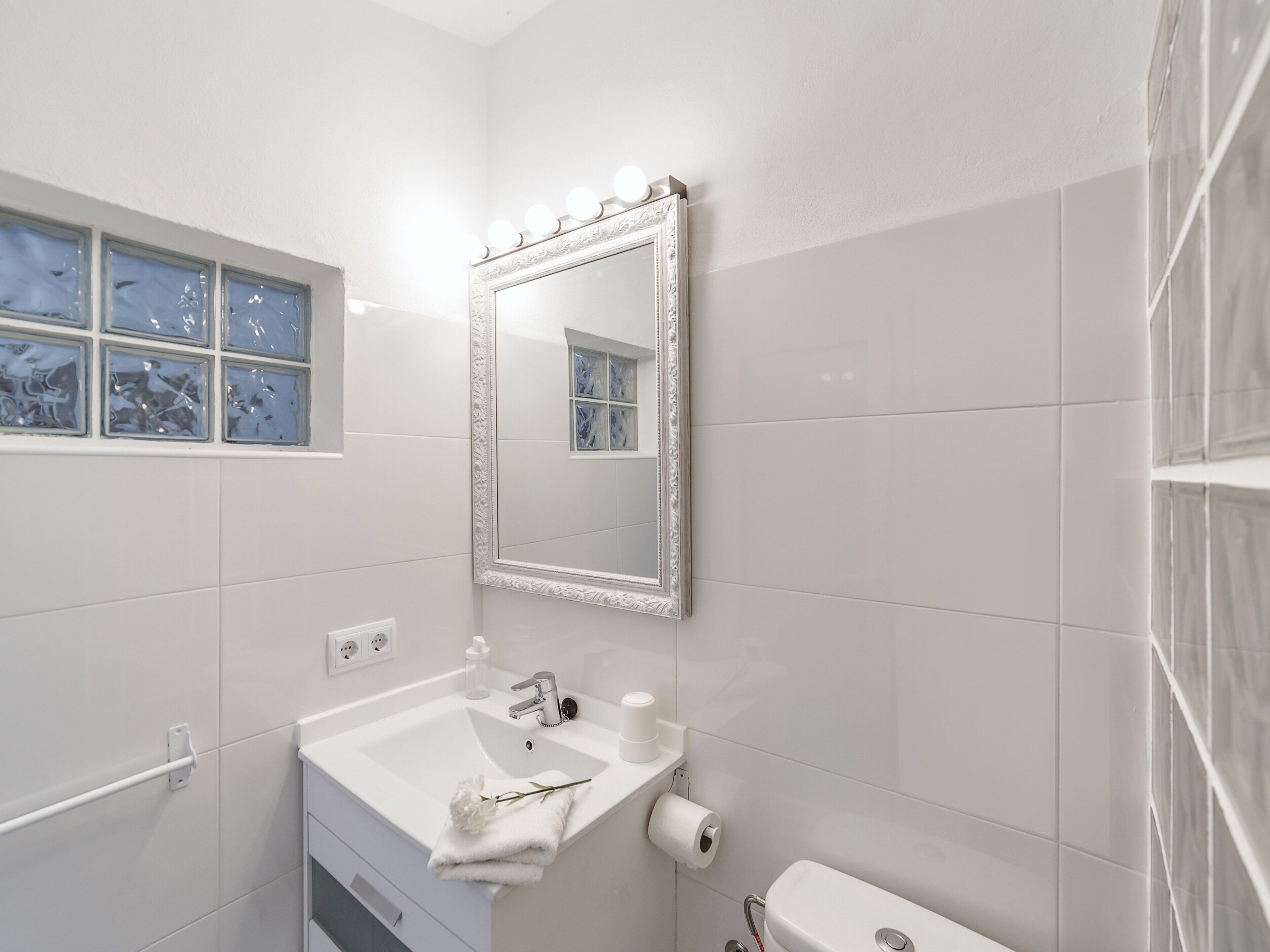 Un baño con lavabo, espejo y retrete.