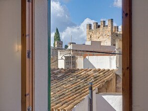 A view through a window of a building with a tiled roof and a stone wall in the background. - House 'Casa con Encanto y Relax, Centro Histórico Alcudia/Mallorca, Aire Acondicionado, 6 Personas' (ALCUDIA)
