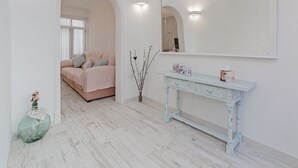 Een slaapkamer met een bed, een kaptafel met spiegel, en een vaas met takken.