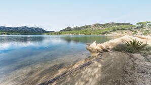 A clear lake with a rocky shoreline and distant mountains. - Rustic Villa, Air Conditioning and Beautiful Garden (Orosei)