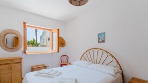A bedroom with a bed, a window, a mirror, a picture on the wall, and a wooden cabinet. - Holiday Home 'Casa Vacanze Cecilia A Otranto' with Sea View, Private Garden & AC (Otranto)