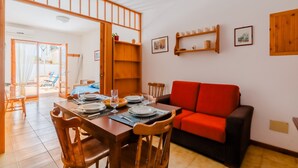 A dining area with a wooden table set for four, a red sofa, and a view through a glass door to an outdoor seating area. - Holiday Home 'Casa Vacanze Cecilia A Otranto' with Sea View, Private Garden & AC (Otranto)